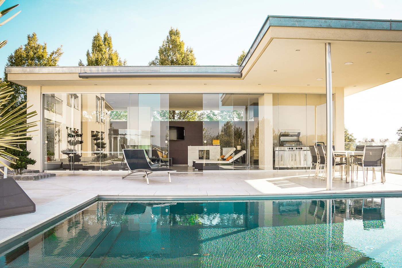 Clean backyard pool in front of a modern glass home
